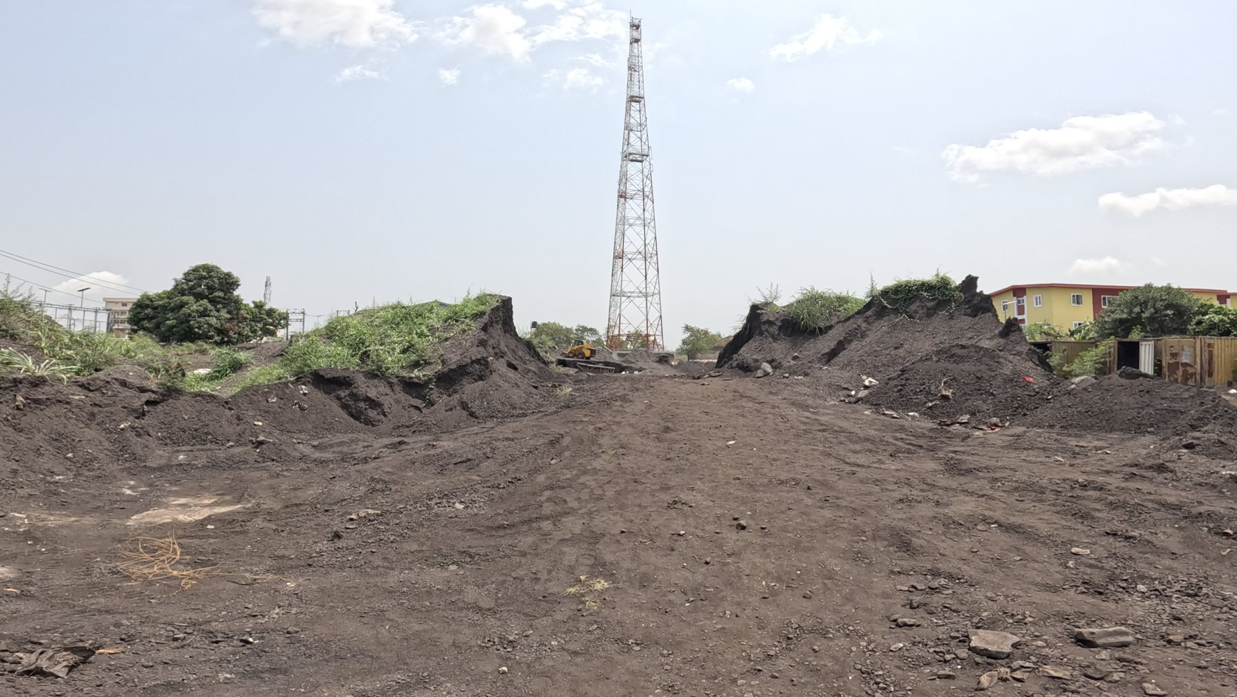 A wide yard of dark spoil heaps under a bright sky